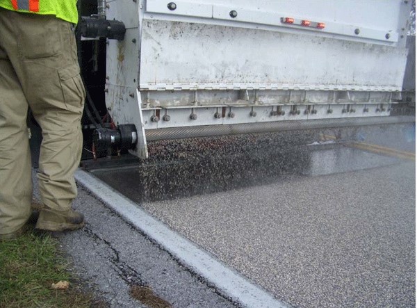 A machine layering a road with high friction surfacing.
